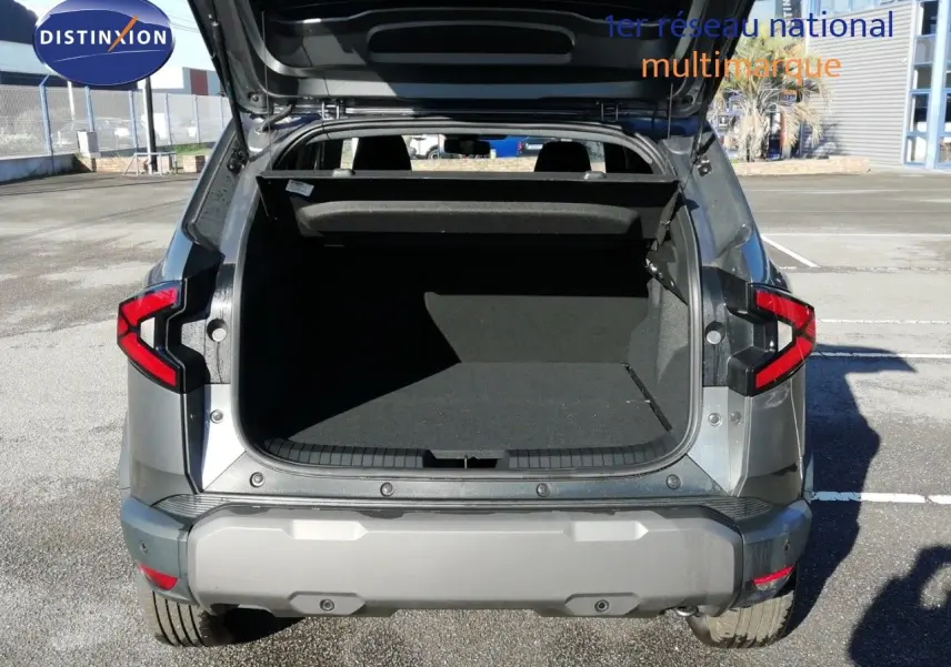 Vue arrière du Dacia Duster TCE MHEV 140ch Journey gris schiste métal avec coffre ouvert et feux arrière allumés.
