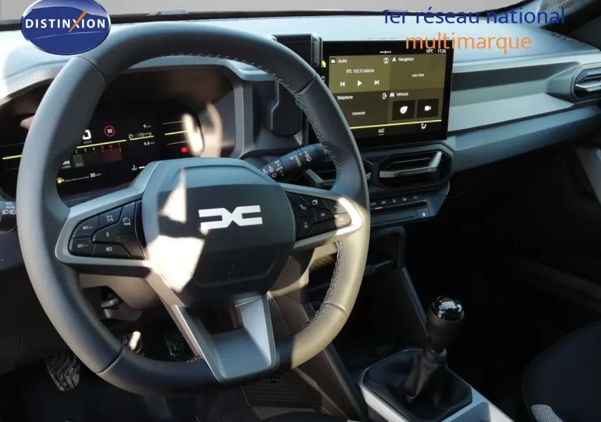 Vue intérieure du poste de conduite du Dacia Duster TCE MHEV 140ch Journey 2026, volant multifonction et écran tactile central.