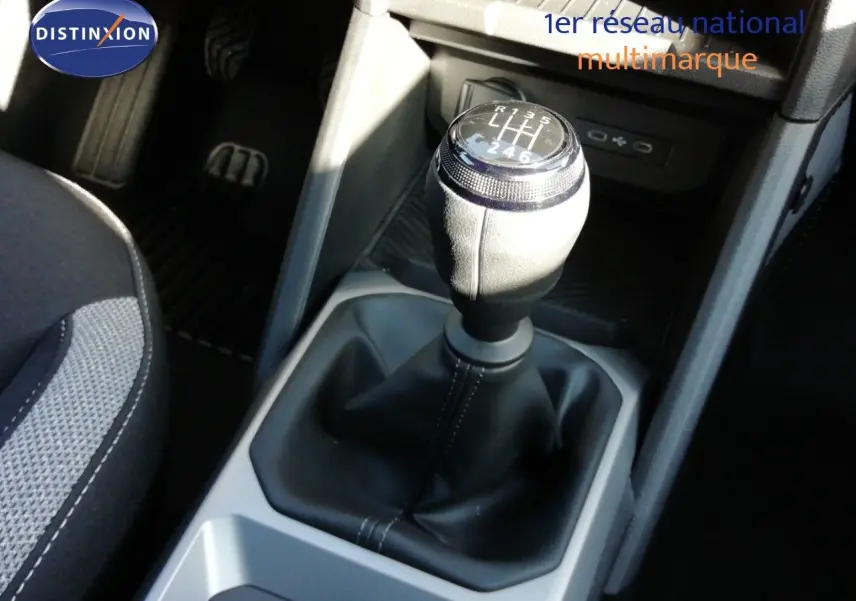 Gros plan sur le levier de vitesses manuel du Dacia Duster gris schiste, avec coutures apparentes et console noire environnante.