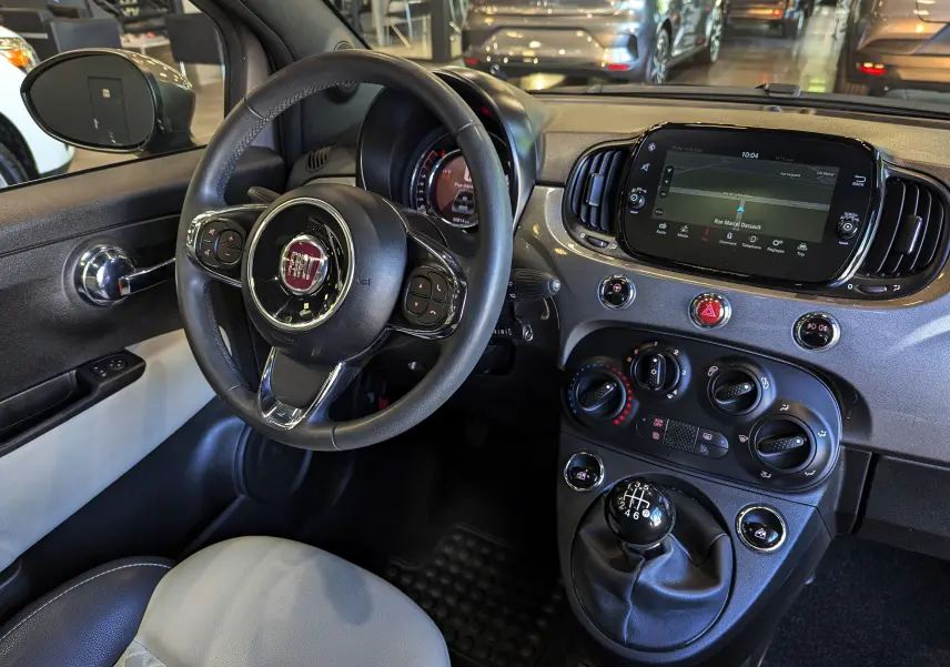 Intérieur de la Fiat 500 Electroclash Grey 2021, vue du poste de conduite avec volant, tableau de bord et levier de vitesses manuel.