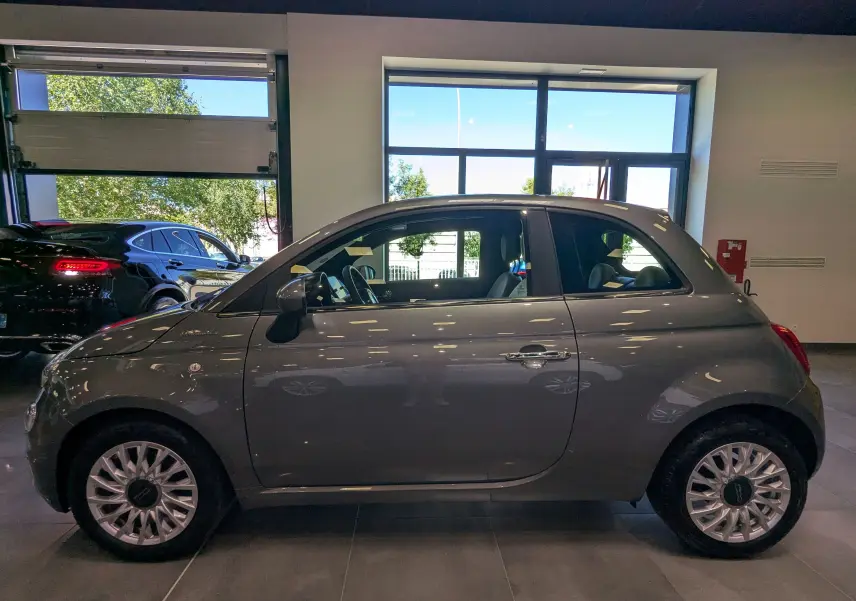 Profil côté gauche d'une FIAT 500 hybride 2021 gris Electroclash, avec jantes alliage et intérieur visible.