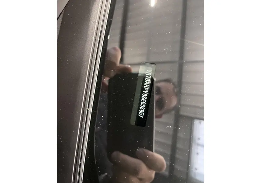 Gros plan sur le pare-brise noir métallisé d'une Citroën C4 2025 montrant le numéro VIN à travers la vitre.