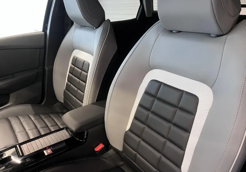 Gros plan sur les sièges avant bicolores noir et gris clair de la Citroën C4 2025 avec accoudoir central.