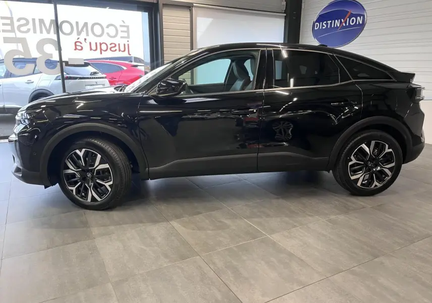 Profil droit d'une Citroën C4 noire métallisée 2025 avec jantes alliage 18'' et rétroviseurs noirs brillants en showroom.