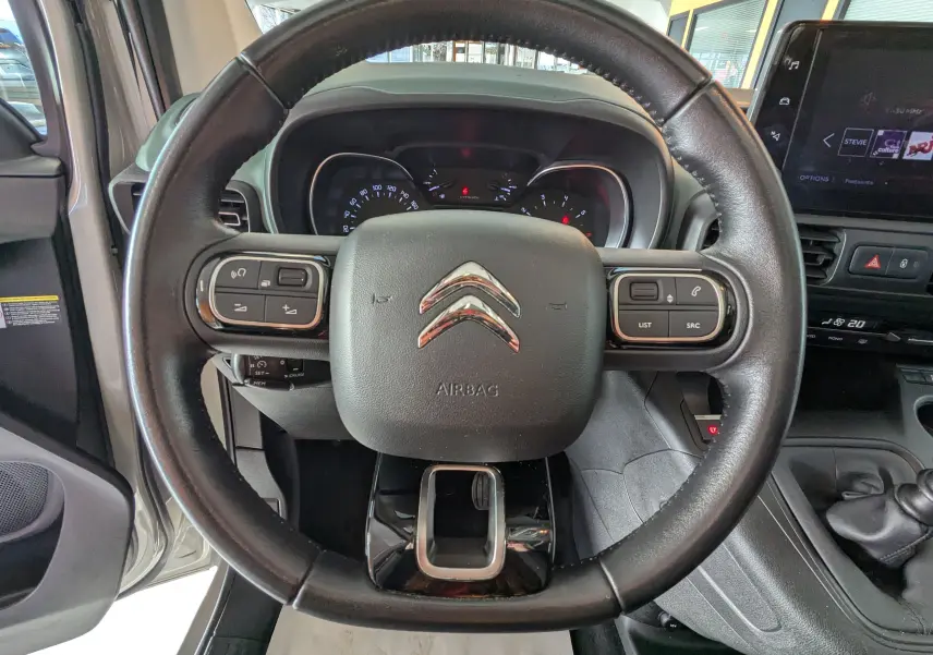 Vue rapprochée du volant noir de la Citroën Berlingo 2019, avec commandes intégrées et tableau de bord visible.