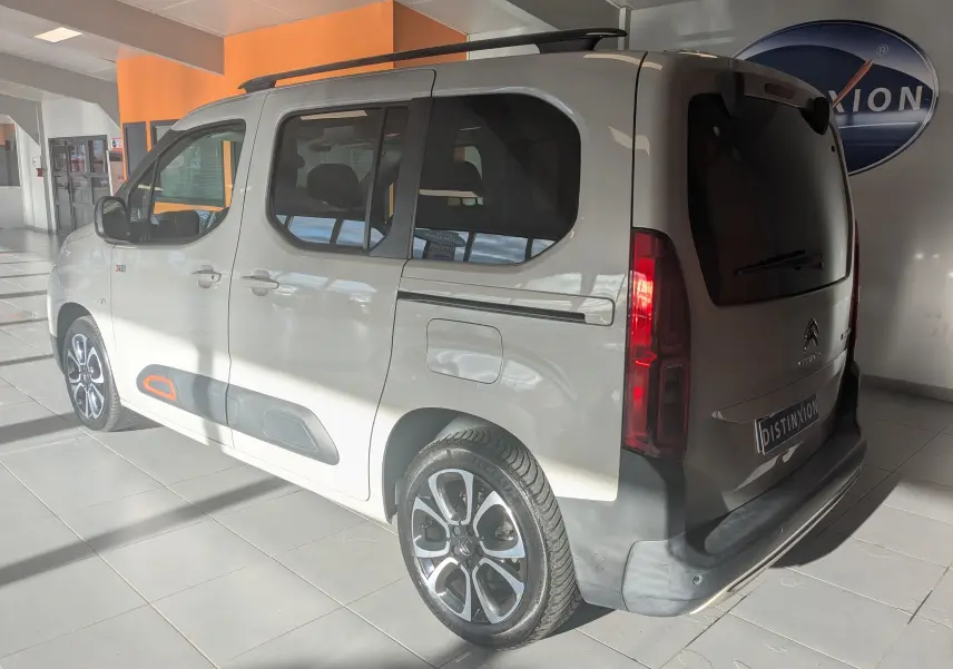 Vue 3/4 arrière droite d'un Citroën Berlingo beige 2019 avec jantes bi-ton et protections latérales noires et orange.
