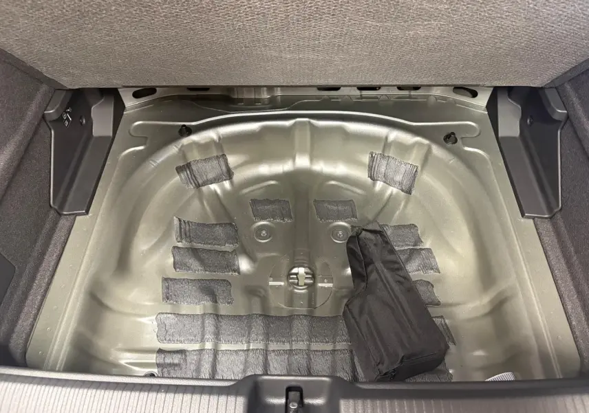 Coffre ouvert de l'Audi Q2 35 TFSI S line 2026 montrant le logement métallique de la roue de secours sans roue.