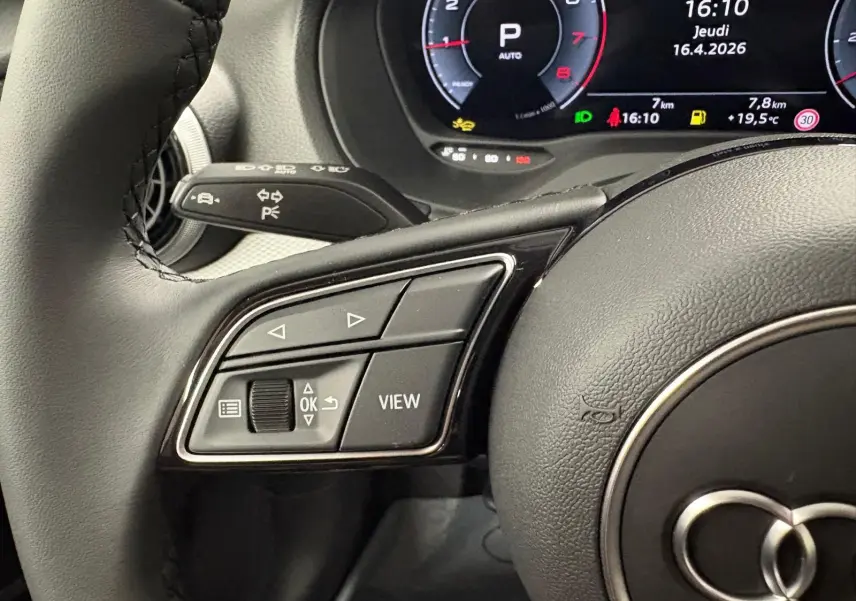 Gros plan sur les commandes au volant à gauche de l'Audi Q2 35 TFSI 150 S Line 2026 avec tableau de bord numérique.