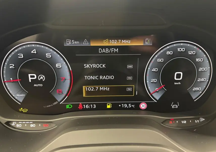 Tableau de bord numérique de l'Audi Q2 35 TFSI 2026 affichant la radio DAB/FM et compte-tours à l'arrêt.