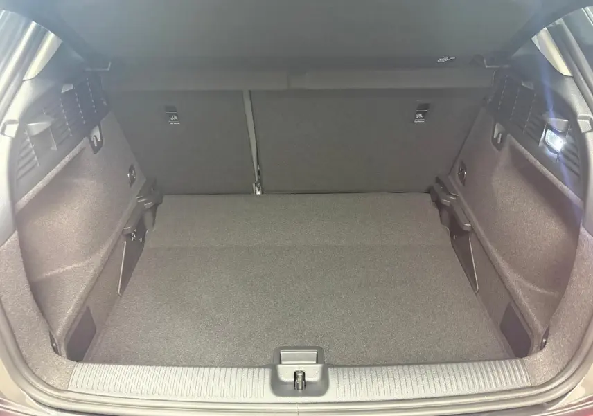 Coffre ouvert vu de l’arrière d’un Audi Q2 35 TFSI S Line gris Daytona, montrant l’espace de chargement vide et l’éclairage intérieur.