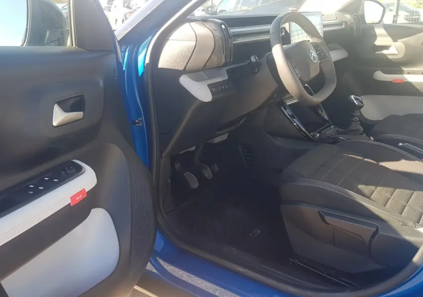 Intérieur avant droit d'une Citroën C3 bleu foncé 2024, montrant siège tissu noir et tableau de bord moderne.