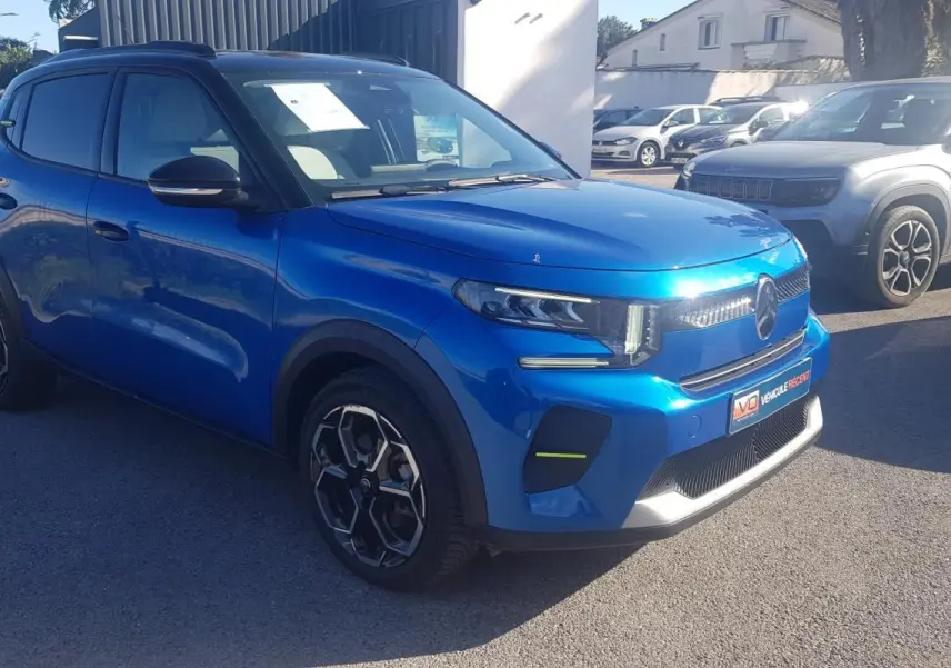 Citroën C3 bleu foncé vue 3/4 avant droit, avec jantes alliage 17 pouces et barres de toit noires.