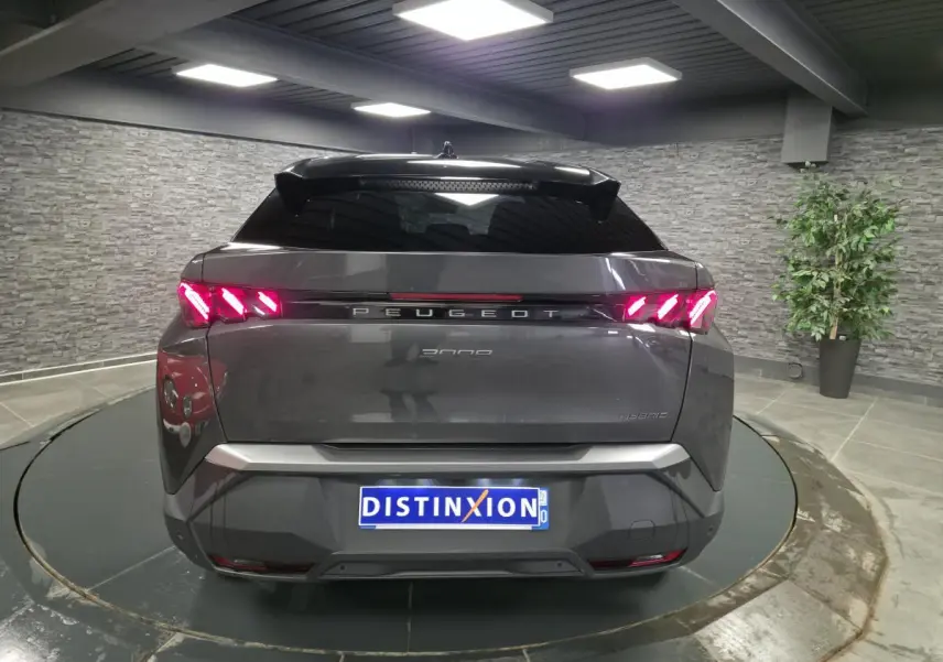 Vue arrière d’un Peugeot 3008 gris métallisé 2025 avec feux arrière LED en forme de griffes et bandeau noir laqué.