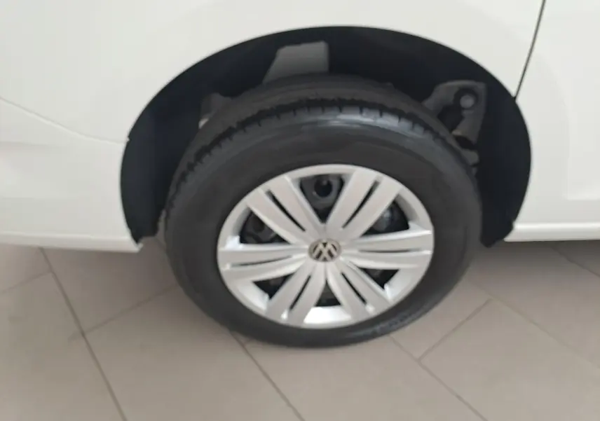 Gros plan sur la roue avant droite d’un Volkswagen Caddy Cargo Maxi blanc Candy avec jante argentée au design moderne.