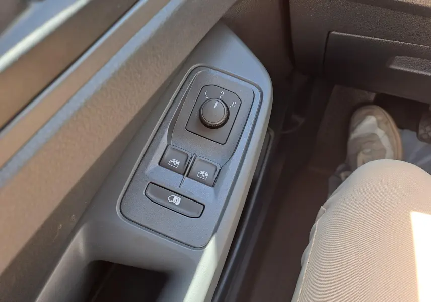 Gros plan sur les commandes de réglage des rétroviseurs et vitres côté gauche du Volkswagen Caddy Cargo Maxi blanc 2026.