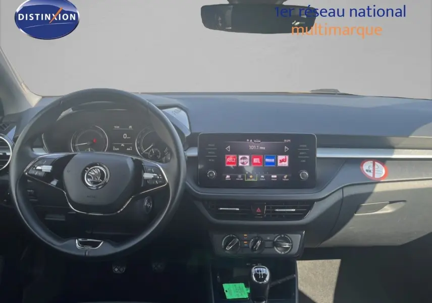 Vue intérieure avant du tableau de bord d'une Skoda Fabia blanche avec volant cuir et écran tactile central.