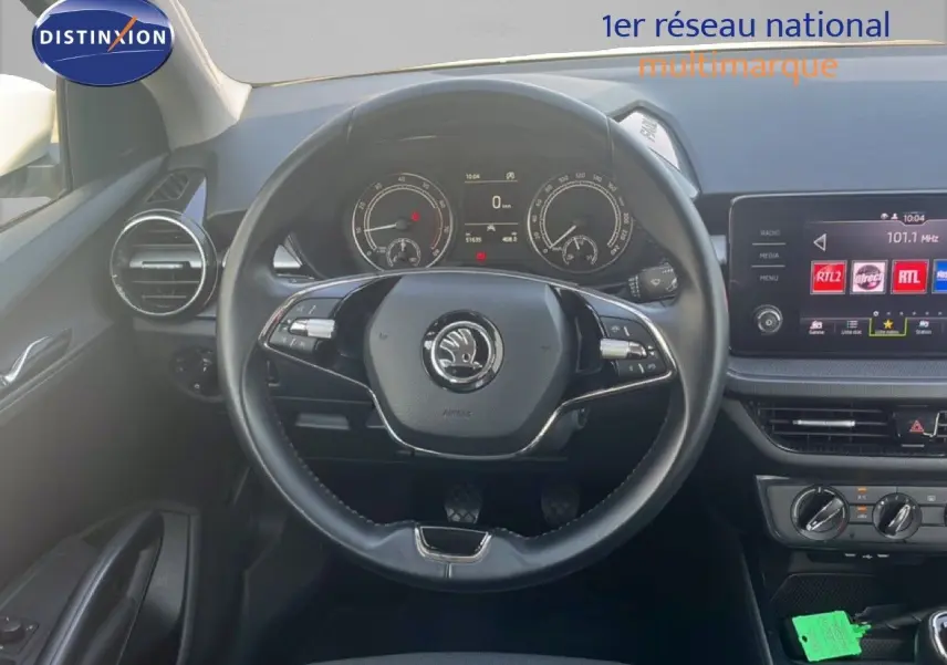 Vue intérieure centrée sur le volant noir et le tableau de bord numérique d'une Skoda Fabia 2022 blanche.