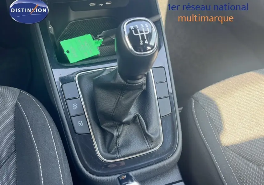 Gros plan sur la boîte manuelle noire et la console centrale de la Skoda Fabia blanche, avec sièges en tissu gris.