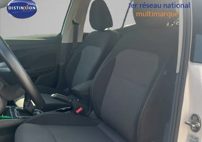 Vue intérieure côté conducteur de la Skoda Fabia blanche, mettant en valeur les sièges en tissu noir et gris.