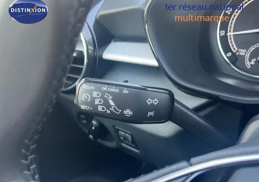 Gros plan sur la commande de régulateur de vitesse à gauche du volant dans l’habitacle d’une Skoda Fabia blanche.