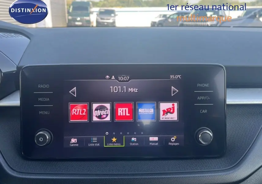 Vue rapprochée de l’écran multimédia central d’une Skoda Fabia blanche, affichant des stations radio.