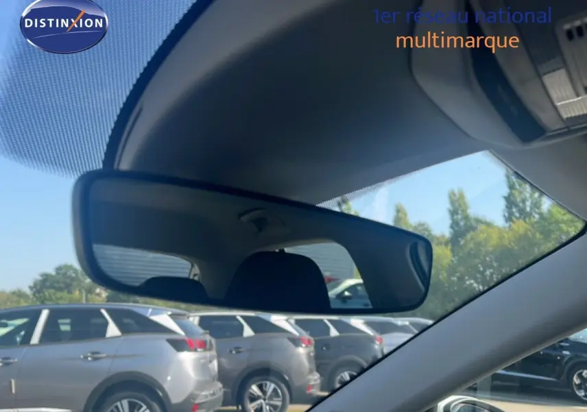Vue intérieure montrant le rétroviseur central d'une Skoda Fabia blanche Candy, avec plusieurs SUV gris en arrière-plan.