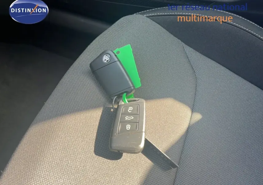 Clé de voiture Skoda posée sur un siège en tissu noir à gris à l'intérieur du véhicule.