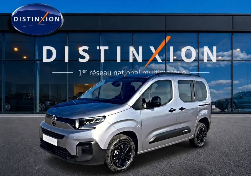 Citroën Berlingo Steel Grey en 3/4 avant droit, avec jantes noires et barres de toit visibles devant showroom Distinxion.