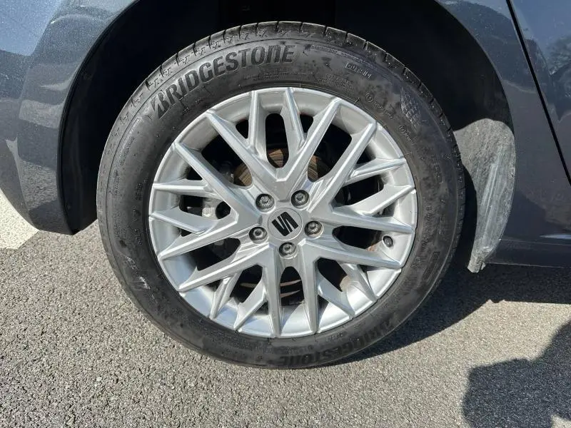 Gros plan sur la roue avant droite d'une SEAT Ibiza 2025 gris magnétique métallisé avec jante alliage à motifs fins.