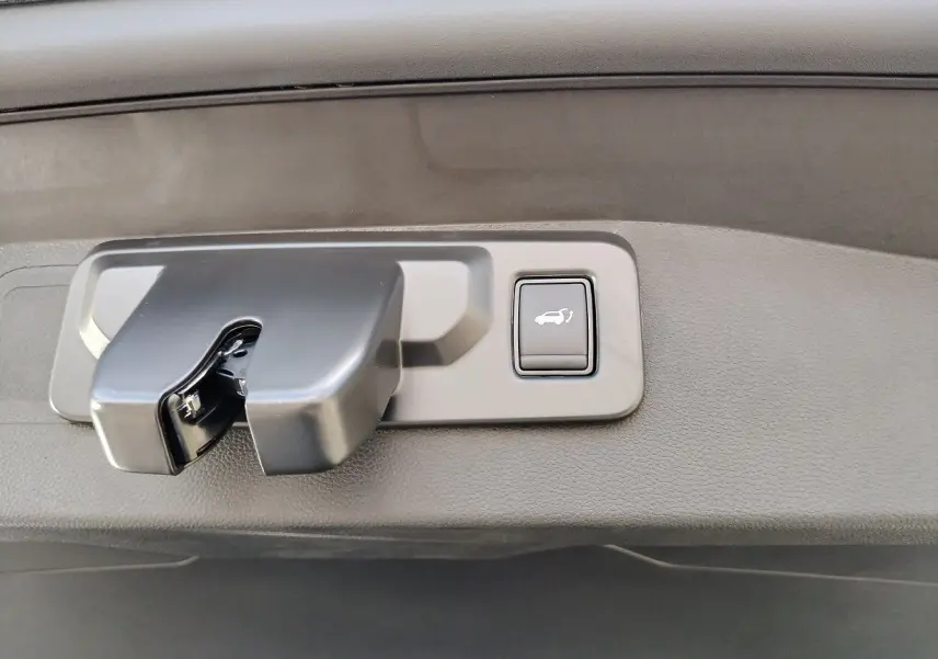 Gros plan sur la poignée de coffre avec bouton d'ouverture électrique du Renault Austral blanc nacré toit noir.