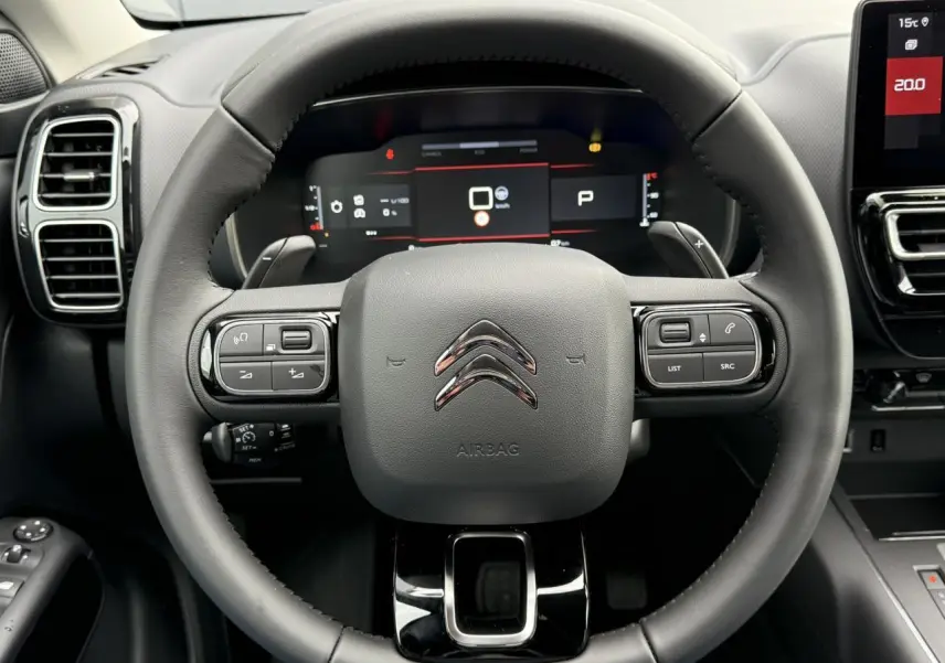 Vue rapprochée du volant noir du Citroën C5 Aircross 2025 avec commandes intégrées et tableau de bord numérique.