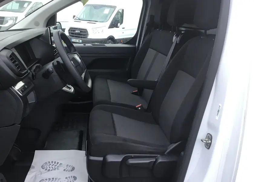 Vue intérieure côté conducteur du FIAT Scudo Fourgon blanc 2024, montrant les sièges avant et le tableau de bord sobre.