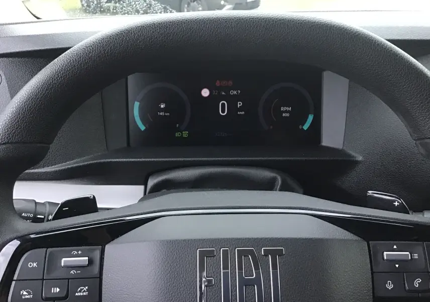 Vue rapprochée du volant noir FIAT avec tableau de bord numérique affichant vitesse et RPM.