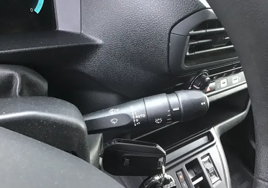 Gros plan sur le commodo d'essuie-glace côté gauche du tableau de bord noir du Fiat Scudo Fourgon blanc 2024.