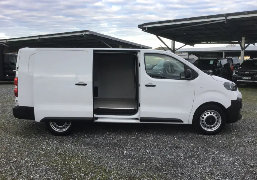 Vue de profil côté droit d'un FIAT Scudo Fourgon blanc 2024 avec porte coulissante ouverte et garde au sol rehaussée.