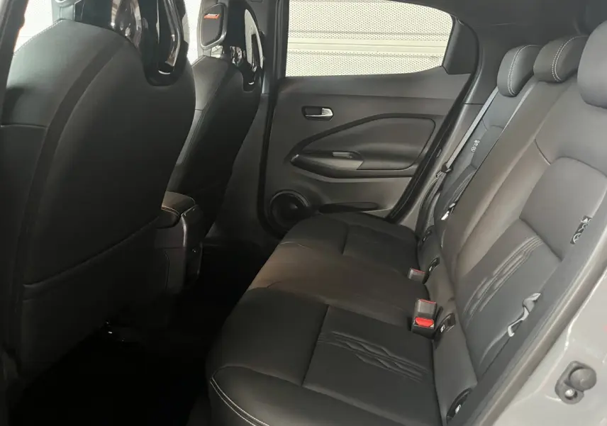 Vue intérieure côté droit des sièges arrière en cuir noir du Nissan Juke Hybrid 2024, avec détails des appuie-têtes et portières.