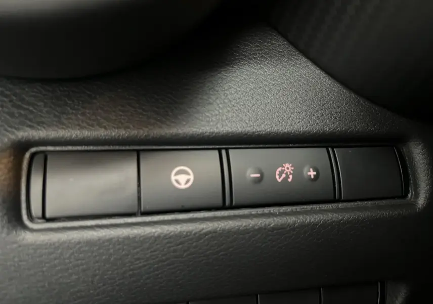 Gros plan sur les boutons de réglage du régulateur de vitesse sur la console intérieure noire du Nissan Juke Hybrid 2024.