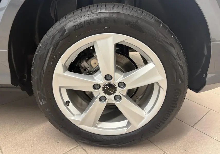 Gros plan sur la roue avant droite d’un Audi Q2 gris Daytona, mettant en valeur la jante alliage 5 branches et le pneu Continental.