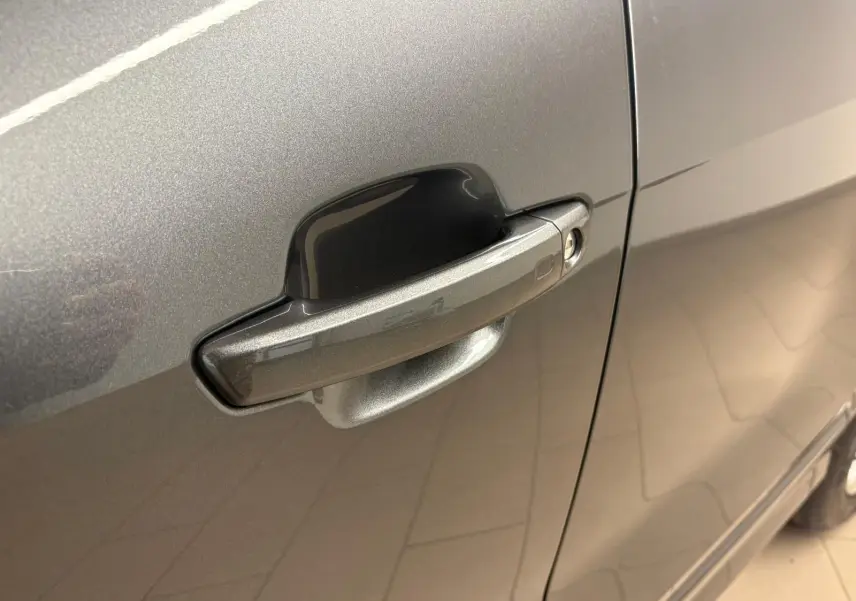 Gros plan sur la poignée de porte côté gauche de l'Audi Q2 35 TFSI S Line gris Daytona métallisé.