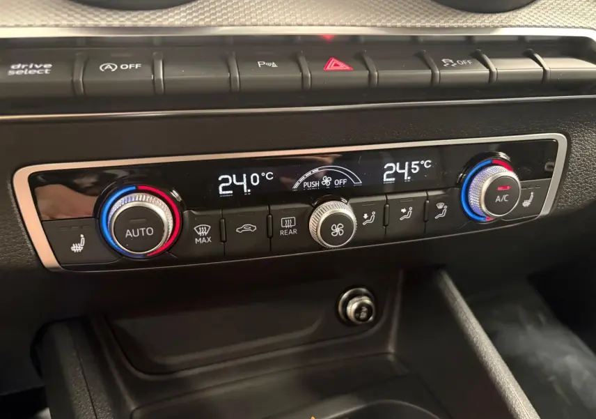 Gros plan sur la console de climatisation automatique de l'Audi Q2 35 TFSI 150 S Line avec réglages numériques et boutons rétroéclairés.