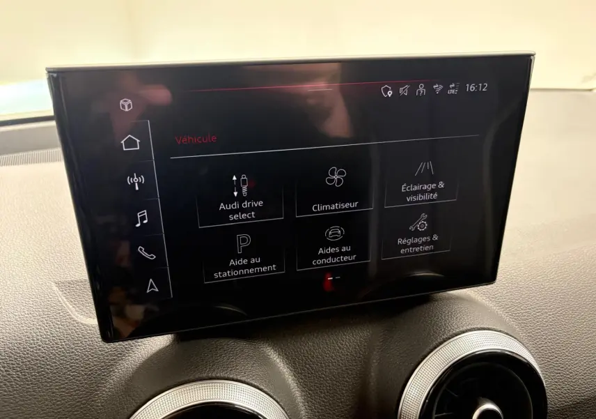 Écran tactile central de l’Audi Q2 35 TFSI S Line 2026, affichant les réglages du véhicule, avec tableau de bord gris.