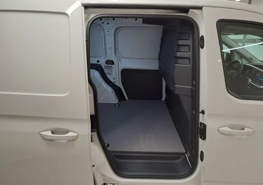 Vue côté droit du Volkswagen Caddy blanc Candy 2025 avec porte coulissante ouverte sur compartiment de charge vide.