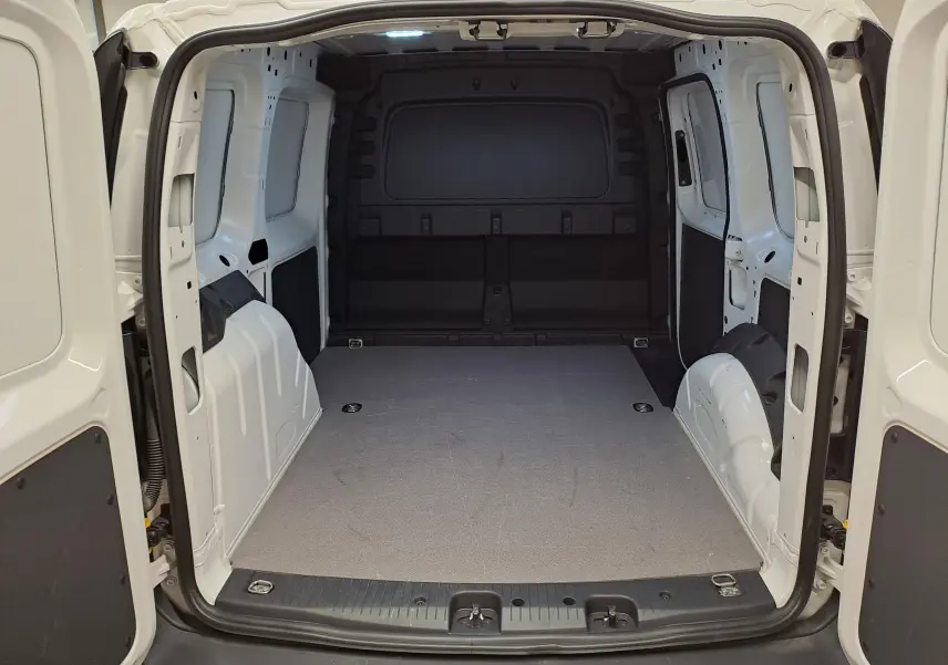 Vue intérieure arrière du coffre blanc du Volkswagen Caddy 2.0 TDI 122 DSG7 Business avec plancher plat et parois métalliques.