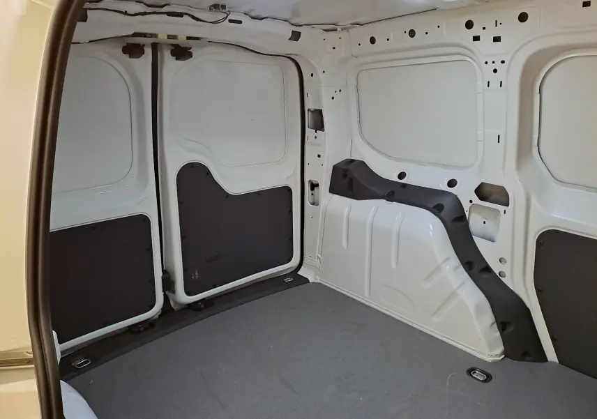 Vue intérieure du compartiment de charge blanc du Volkswagen Caddy 2.0 TDI 122 DSG7 Business avec revêtement gris et protections noires.