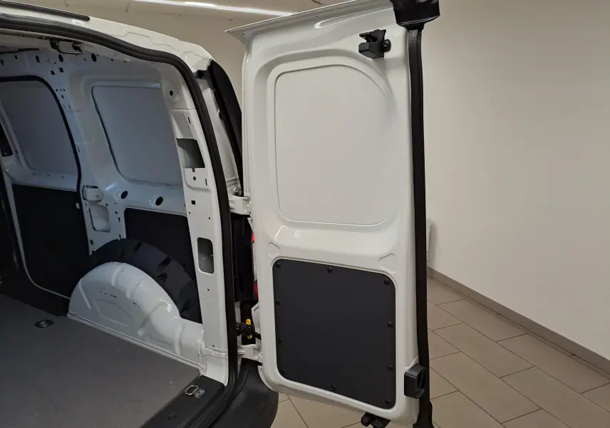 Vue intérieure arrière de la porte droite ouverte du Volkswagen Caddy blanc Candy, montrant le compartiment de charge vide.
