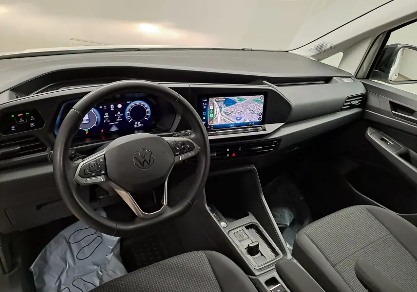 Vue intérieure du tableau de bord et volant noir du Volkswagen Caddy 2025 avec écran tactile central et digital cockpit.