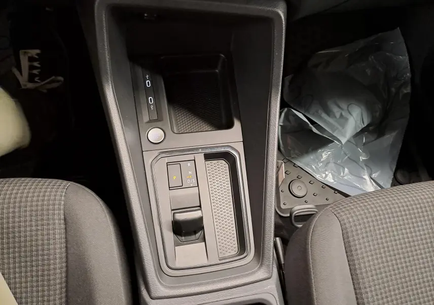 Vue intérieure centrée sur la console centrale avec levier de vitesses automatique et bouton start/stop du Volkswagen Caddy 2025.