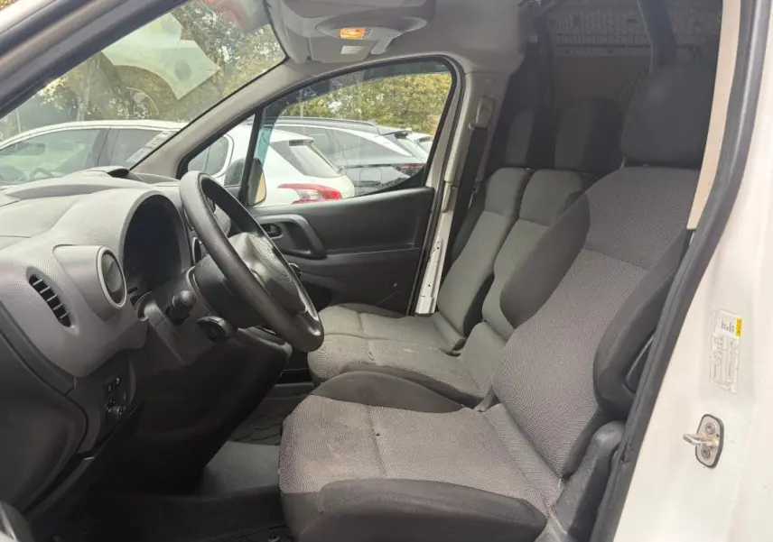 Vue intérieure côté conducteur du Citroën Berlingo blanc 2018, montrant les sièges avant et le tableau de bord simple.