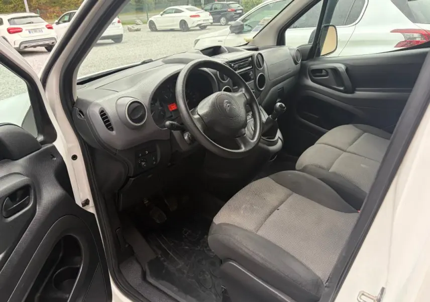 Vue intérieure côté conducteur du Citroën Berlingo blanc 2018, montrant le tableau de bord et les sièges avant gris.