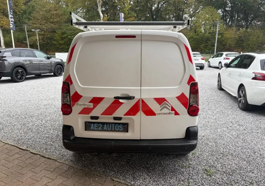Vue arrière d’un Citroën Berlingo blanc 2018 avec bandes rouges réfléchissantes et porte-échelle sur le toit.